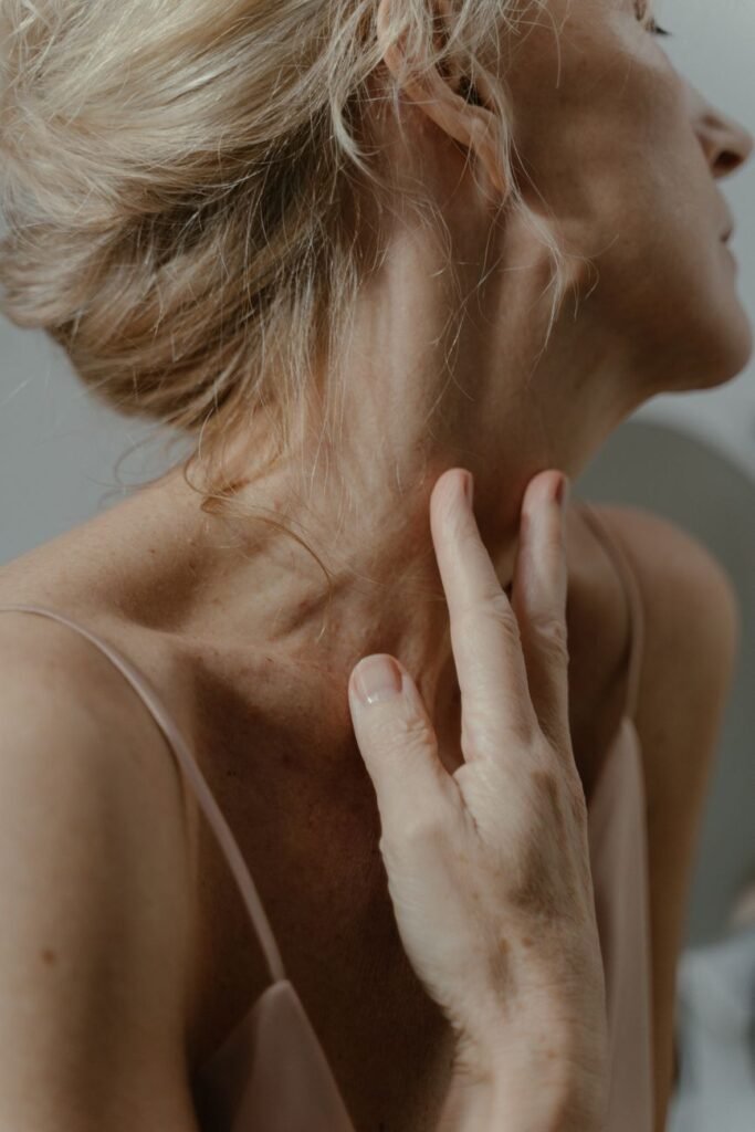 elderly blonde woman touching neck